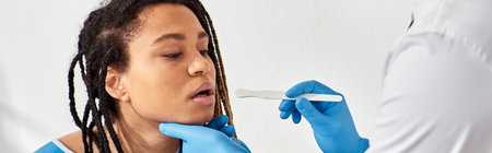 young ill african american woman in hospital ward having doctor check up of throat, healthcareの写真素材