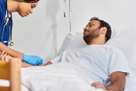 young african american nurse inserting catheter into arm of her sick indian patient, healthcareの写真素材