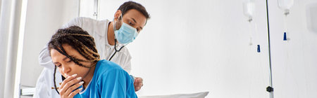 young indian doctor examining breath of his ill african american patient with stethoscope, bannerの写真素材