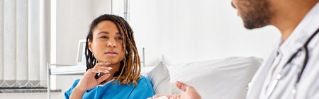 african american woman in hospital bed looking at her indian doctor taking notes on tablet, bannerの写真素材
