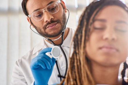 focus on doctor checking breath of his blurred african american patient in hospital ward, healthcareの写真素材