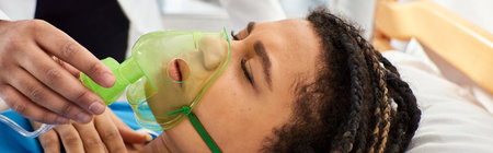 cropped view of doctor comforting ill african american woman lying in bed with oxygen mask, bannerの写真素材