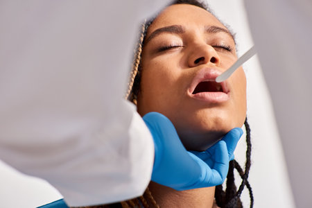 cropped view of doctor checking up throat of his young african american female patient, healthcareの写真素材