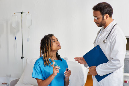 young indian doctor teaching his ill african american female patient how to use asthma inhalerの写真素材