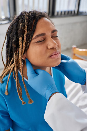 young indian doctor examining lymph nodes of his ill african american female patient, healthcare