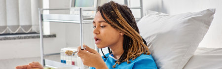 young african american woman having porridge and apple for breakfast in her hospital ward, bannerの写真素材