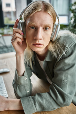 portrait of young androgynous person in casual attire with headphones looking at camera, businessの写真素材