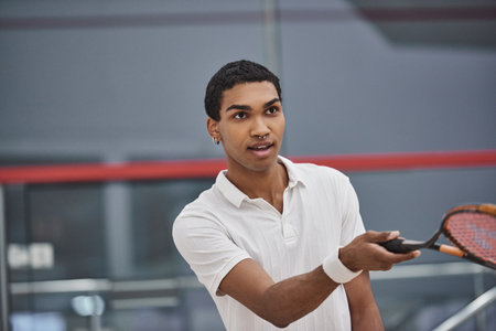 pierced african american sportsman playing squash inside of court, challenge and motivationの写真素材