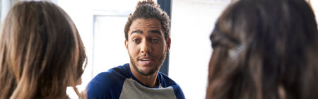 inspired african american man talking and sharing ideas with female colleagues in office, bannerの写真素材