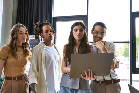 thoughtful multiethnic team looking at laptop while working on new business project in officeの写真素材