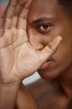 close up of handsome appealing african american man with hand in front of face, fashion concept