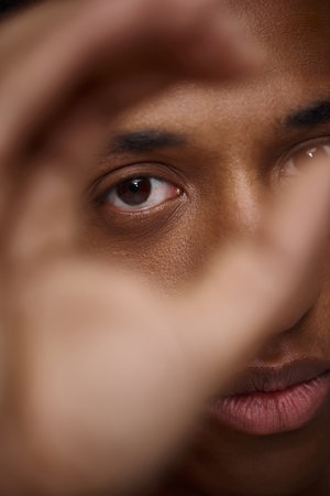 close up of handsome appealing african american man with hand in front of face, fashion concept