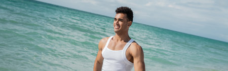 Muscular cuban young man walking ocean water of Miami South Beach, Florida, banner