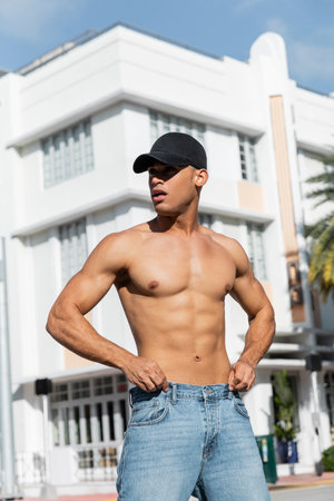 good looking cuban man with athletic body in baseball cap on urban street in Miami, during summer