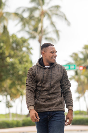 happy african american man in hoodie and jeans walking on street in Miamiの写真素材