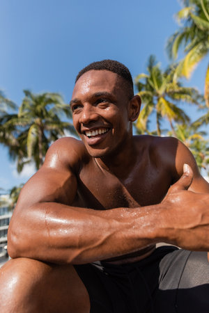 portrait of sweaty and happy african american sportsman without shirt looking away after workoutの写真素材