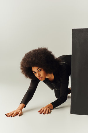 beautiful african american female model in black bodysuit posing next to black cube, fashion conceptの写真素材
