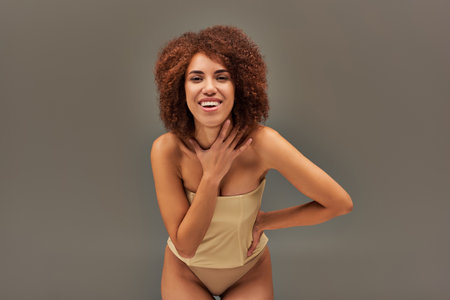 happy attractive african american woman in pastel underwear smiling cheerfully, fashion conceptの写真素材
