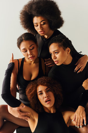 attractive african american women in black alluring outfits posing on black cube, fashion conceptの写真素材