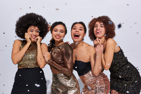 beautiful stylish african american women partying in vibrant attires under confetti rain, fashionの写真素材
