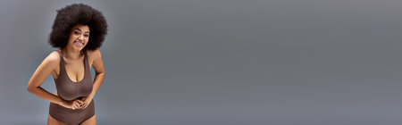 cheerful african american female model in pastel underwear smiling happily, fashion concept,  bannerの写真素材