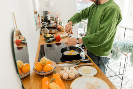 Cropped view of bearded man seasoning fried eggs with peppercorns from millの写真素材