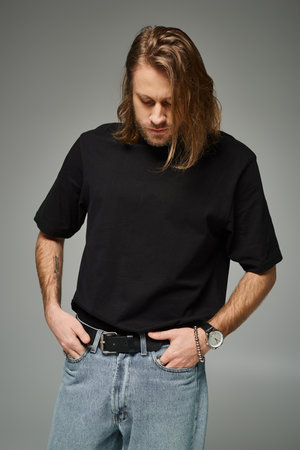 bearded and handsome man with long hair posing, tattoo translation: Love conquers all