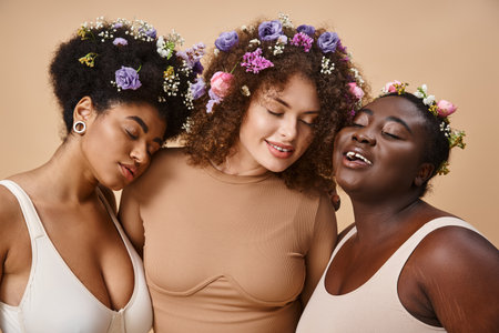 multiracial plus size women in lingerie with colorful flowers in hair and closed eyes on beigeの写真素材