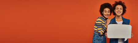 emotional young african american siblings posing with speech bubble on orange backdrop, familyの写真素材