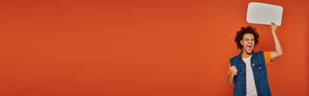 jolly african american man in casual attire posing with speech bubble on orange backdrop, bannerの写真素材