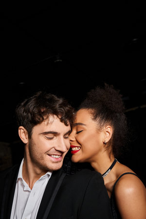 multicultural joyous couple in evening attire posing lovingly and smiling happily, Valentines day