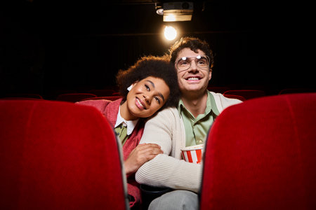 cheerful african american woman with her head on shoulder of her handsome boyfriend at cinemaの写真素材