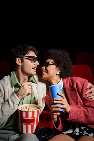 joyful multicultural couple in retro attires smiling joyfully at each other on date at cinemaの写真素材