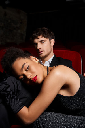 appealing young multiracial couple in black elegant outfits posing at cinema, Valentines day