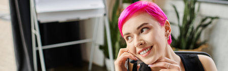 cheerful tattooed woman in casual urban outfit talking by phone at office, business concept, banner