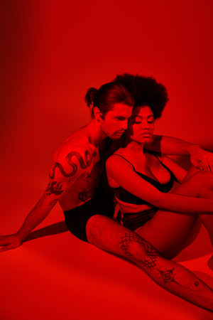 handsome man with tattoos posing alluringly with his pretty african american girlfriend, sexy coupleの写真素材