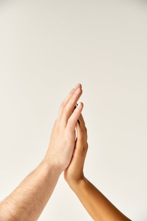 cropped view of interracial sexy couple touching hands and fingers of each other on ecru backgroundの写真素材