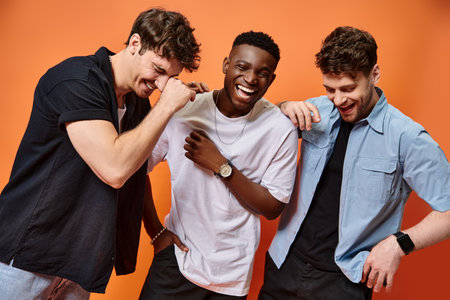 happy trendy multicultural men in urban casual outfits smiling cheerfully together, fashion concept