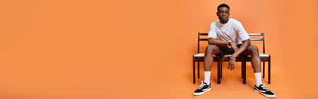 handsome young african american man in urban outfit sitting on bench, fashion concept, bannerの写真素材
