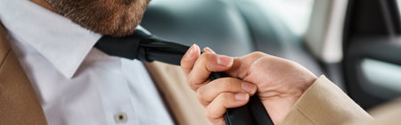 cropped view of seductive woman pulling tie on bearded business colleague in car, horizontal bannerの写真素材