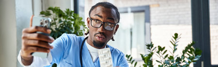 focused african american doctor consulting patient by phone and holding pills, telemedicine, banner