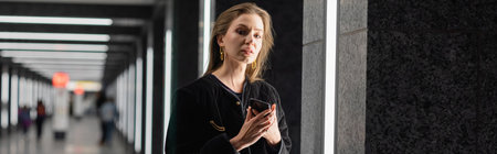 trendy young woman in black jacket posing in building with fluorescent lamps in Berlin, banner