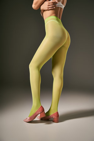 cropped view of young woman in green nylon tights and bra posing on grey background, hosiery conceptの写真素材