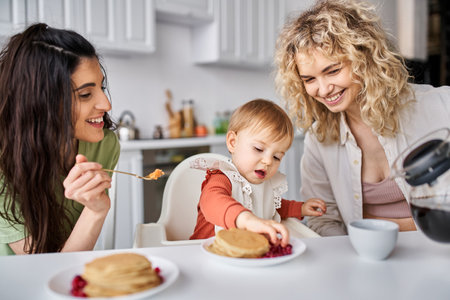 happy beautiful lgbt couple having delicious breakfast with their baby girl, family conceptの写真素材