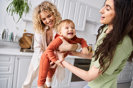 attractive jolly lesbian couple spending time together with their toddler daughter, modern parentingの写真素材