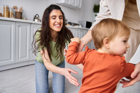 attractive happy lgbt couple playing actively with their cute toddler daughter, modern parentingの写真素材