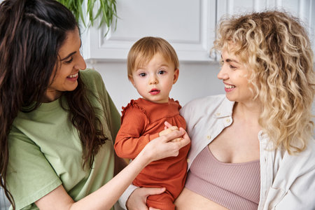 bonded happy lesbian couple spending time together with their toddler daughter, modern parentingの写真素材