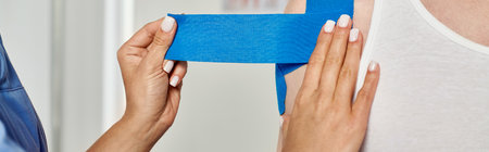 cropped view of hand of female doctor putting kinesio tapes on her male patient, healthcare, bannerの写真素材