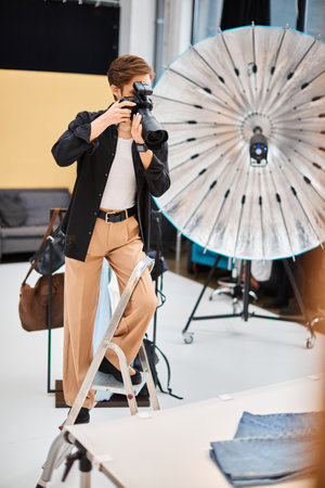 good looking young woman in casual attire taking photos with her modern camera in her studioの写真素材