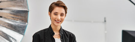 jolly pretty professional female photographer in casual attire smiling and looking at camera, bannerの写真素材